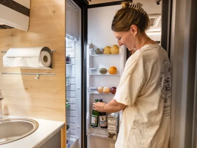 Dethleffs Globebus Go Küche mit Frau am Kühlschrank