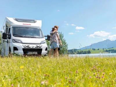 Dethleffs Just Camp Teilintegrierter mit Personen am Seeufer
