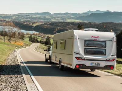 Dethleffs Wohnwagen auf kurviger Straße mit Berglandschaft im Hintergrund
